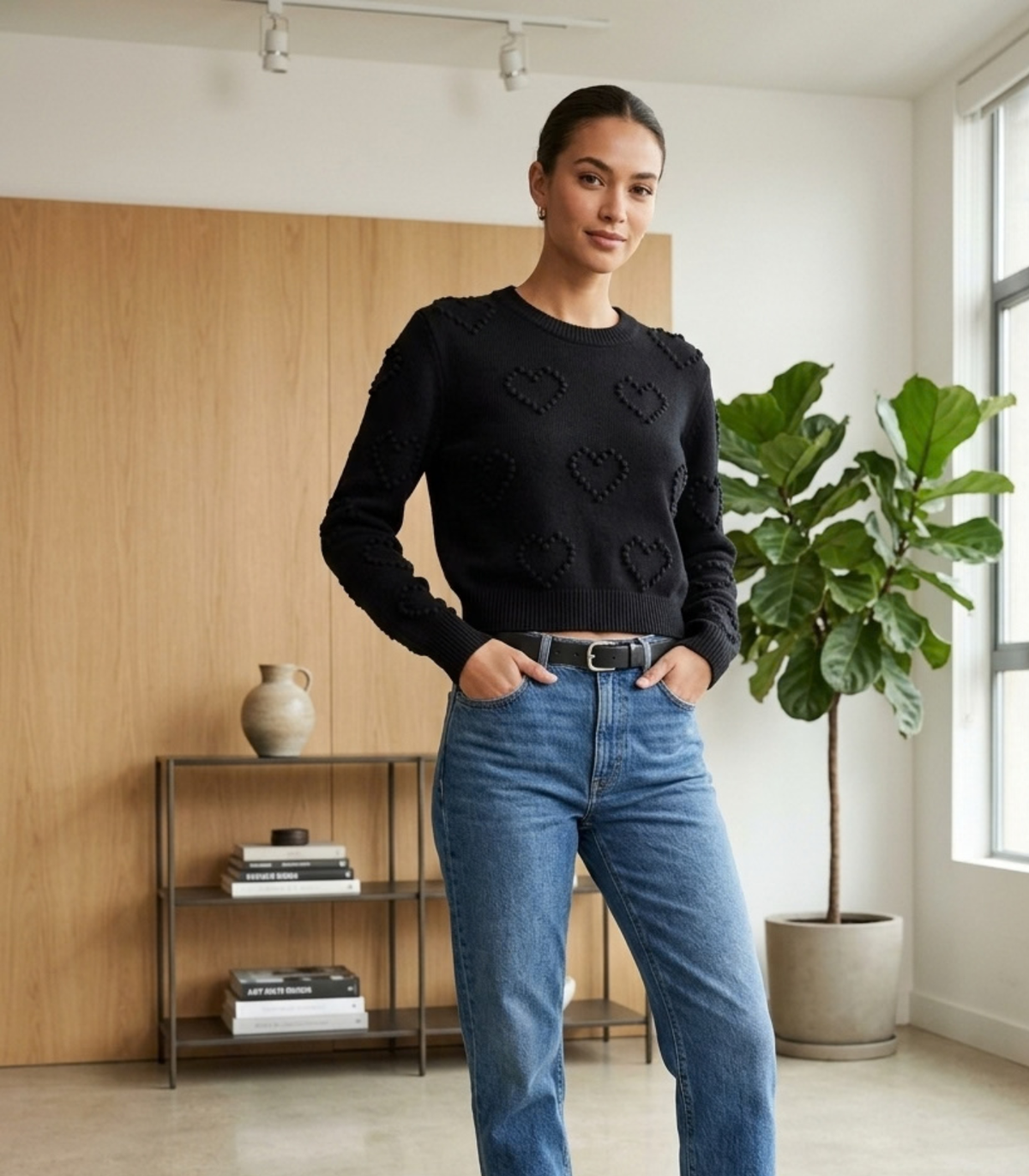 Model trägt schwarzen Strickpullover mit Herzchen-Muster